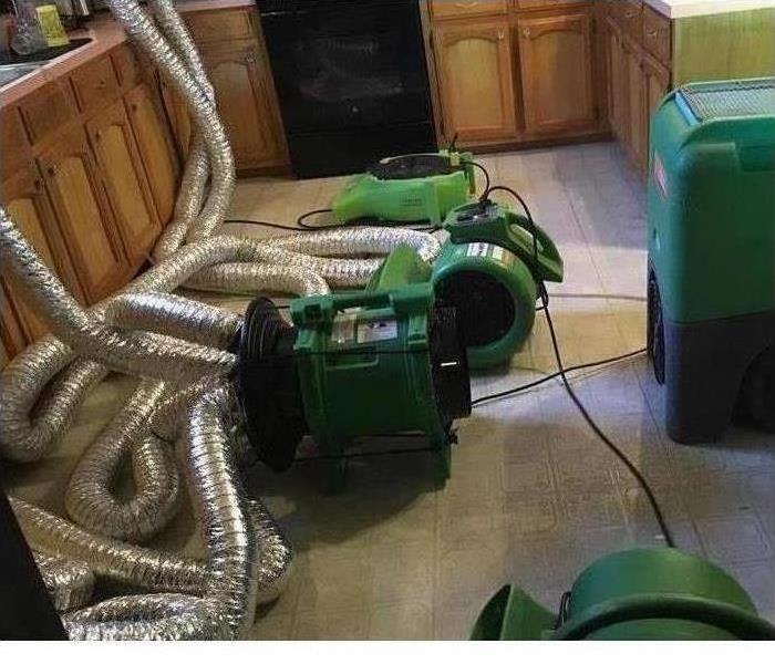 Wet floor and cabinets with drying equipment around .